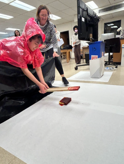 Senior Rhia Basit uses a stick on a bloody sponge to create blood spatter. 